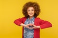 Love you! Portrait of romantic beautiful woman with curly hair showing heart gesture and smiling kindly, expressing care