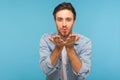 Love you! Portrait of stylish handsome man in denim shirt sending air kiss over palms, flirting to camera Royalty Free Stock Photo