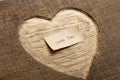 Love you - tiny typed text note close up. Valentines Day greetings concept. Carved heart shape on wood as background for Royalty Free Stock Photo