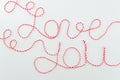 Love you words written with woolen red and white thread lettering, concept and isolated white background for Valentine`s