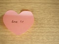 Love you, writing on sticky note, heart shape on wood background Royalty Free Stock Photo