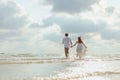 Love young couple holding hands and running on the beach. Holiday and vocation concept