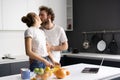 In love young couple kissing while preparing food at kitchen. Husband kiss his wife while she cut oranges and watching Royalty Free Stock Photo