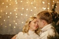 Love young happy family, the couple kissing, sitting near the Christmas tree in the room. Happy New Year and Christmas Royalty Free Stock Photo