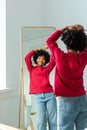 Love yourself. Beautiful young smiling african american woman dancing touching curly hair enjoying her mirror reflection Royalty Free Stock Photo