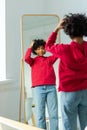 Love yourself. Beautiful young smiling african american woman dancing touching curly hair enjoying her mirror reflection Royalty Free Stock Photo