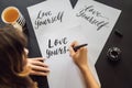 Love yourself. Calligrapher Young Woman writes phrase on white paper. Inscribing ornamental decorated letters