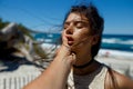 A loved one touches his girlfriend`s lips, passion, love affair on the beach of the Corsica island, seascape background.