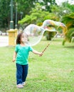 Lovely active little asian girl playing with soap bubble outdoor in the park Royalty Free Stock Photo