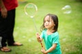 Lovely active little asian girl playing with soap bubble outdoor in the park Royalty Free Stock Photo