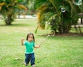 Lovely active little asian girl playing with soap bubble outdoor in the park Royalty Free Stock Photo