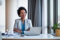 Lovely african-american businesswoman, looking away, sitting at her desk Royalty Free Stock Photo