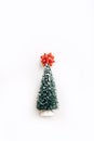 Lovely artificial mini Christmas tree with red bow on top over white background. Little Christmas tree Royalty Free Stock Photo