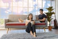 Lovely Asian couple in living room at home. young woman with headphone sit on floor playing video game, man lying on couch working Royalty Free Stock Photo