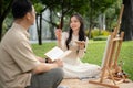 A lovely Asian girl enjoys painting with her dad in a park, picnicking, and spending time together Royalty Free Stock Photo