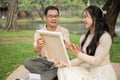 A lovely Asian girl enjoys picnicking in a park with her dad, paint a picture on a canvas together Royalty Free Stock Photo