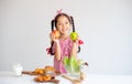 Lovely Asian little girl hold apples and smile with vegetables, milk and bread on table with white wall background