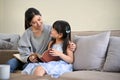 Lovely Asian mom reading a book or telling a funny fairytale story to her cute young daughter Royalty Free Stock Photo