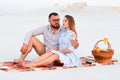 Lovely attractive couple sitting together on the white sand beach, happy couple sitting on a blanket , happy couple enjoying picni Royalty Free Stock Photo