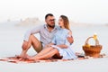 Lovely attractive couple sitting together on the white sand beach, happy couple enjoying picnic on the beach and have good time on Royalty Free Stock Photo