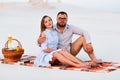 lovely attractive couple sitting together on the white sand beach, happy couple sitting on a blanket , happy couple enjoying Royalty Free Stock Photo