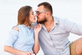 lovely attractive couple sitting together on the white sand beach, looking each other, young couple kissing on the beach, love, r Royalty Free Stock Photo