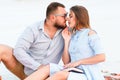 Lovely attractive couple sitting together on the white sand beach, looking each other, young couple kissing on the beach, love, ro Royalty Free Stock Photo