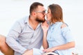 Lovely attractive couple sitting together on the white sand beach, looking each other, young couple kissing on the beach, love, ro Royalty Free Stock Photo