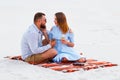 Lovely attractive couple sitting together on the white sand beach, couple with wine or champagne during romantic dinner, young cou Royalty Free Stock Photo