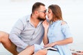 Lovely attractive couple sitting together on the white sand beach, young couple kissing on the beach Royalty Free Stock Photo