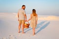 lovely attractive couple on the white sand beach or in the desert or in the sand dunes, guy and a girl with a basket in their han Royalty Free Stock Photo