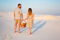 Lovely attractive couple on the white sand beach or in the desert or in the sand dunes, guy and a girl with a basket in their hand Royalty Free Stock Photo