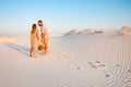 Lovely attractive couple on the white sand beach or in the desert or in the sand dunes, guy and a girl with a basket in their hand Royalty Free Stock Photo