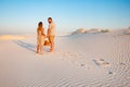 Lovely attractive couple on the white sand beach or in the desert or in the sand dunes, guy and a girl with a basket in their hand Royalty Free Stock Photo