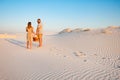 Lovely attractive couple on the white sand beach or in the desert or in the sand dunes, guy and a girl with a basket in their hand Royalty Free Stock Photo