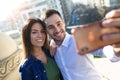 Lovely attractive smiling couple taking selfie with their mobile phone in the street