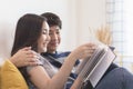 Lovely attractive young Asian couple man and woman with happy smile and reading book in romantic moment. Warm heart marriage and l