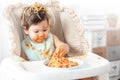 Lovely baby girl eating spaghetti and making a mess. Family leave baby alone, eating pasta herself