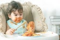 Lovely baby girl eating spaghetti and making a mess. Family leave baby alone, eating pasta herself Royalty Free Stock Photo