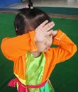 A lovely baby girl is raising her hand on her face with a Vietnamese traditional four-part dress