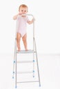 Lovely baby girl standing on top of ladder smiling Royalty Free Stock Photo