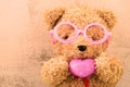 Lovely bear doll wearing pink glasses and holding heart sh Royalty Free Stock Photo