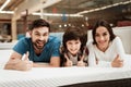 Bearded man, together with his beautiful wife and son, relaxes on the mattress in the store.