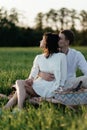 Lovely beautiful couple in love sitting on the green grass at sunset. Romantic love story in the park. Royalty Free Stock Photo