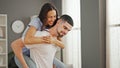 Lovely beautiful couple, two people in love, smiling confidently while man is holding his laughing girlfriend on his back, Royalty Free Stock Photo