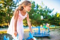 A lovely beautiful girl in a pink delicate dress sits on a small swing in a sunny summer park