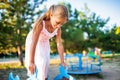 A lovely beautiful girl in a wonderful pink delicate dress sits on a small swing in a warm sunny summer park