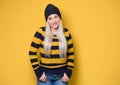 Lovely beautiful young woman smiling while standing with hands in pockets, model wearing woolen cap and sweater, isolated on Royalty Free Stock Photo