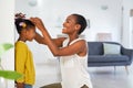 Lovely black mother measuring daughter height against wall at home