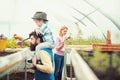 Lovely blond lady in pink cardigan planting flowers with little gardening spade. Side view bearded man holding kid in